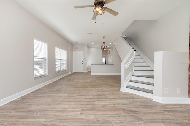 10966 Winter Crest Dr, Riverview, FL 33569 - unfurnished living room featuring light wood-type flooring, a ceiling fan, stairs, and a chandelier