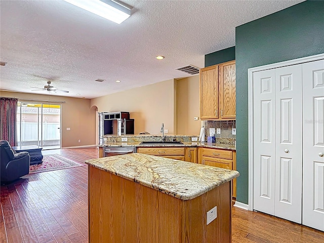 3824 Duke Firth St, Land O Lakes, FL 34638 - kitchen featuring a peninsula, a textured ceiling, open floor plan, light wood-style flooring, and light stone countertops