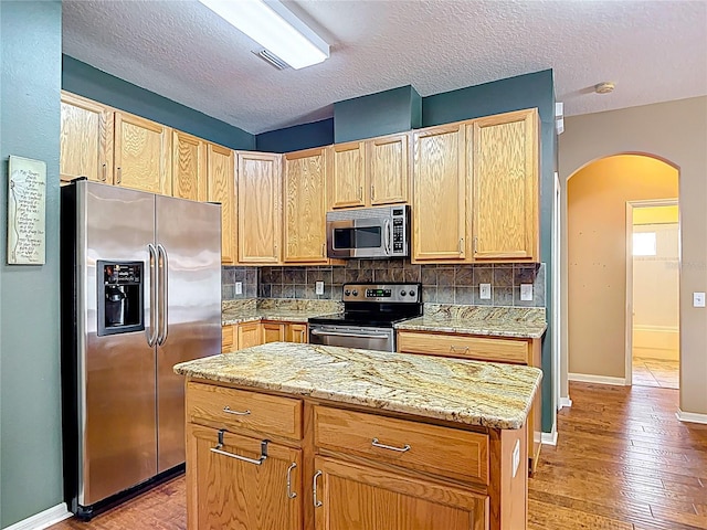 3824 Duke Firth St, Land O Lakes, FL 34638 - kitchen featuring stainless steel appliances, arched walkways, tasteful backsplash, a textured ceiling, and light wood-style floors