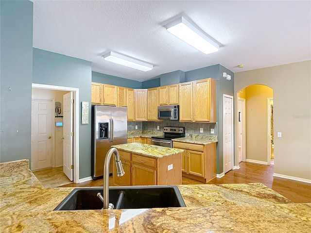3824 Duke Firth St, Land O Lakes, FL 34638 - kitchen with stainless steel appliances, arched walkways, decorative backsplash, a center island, and light stone countertops