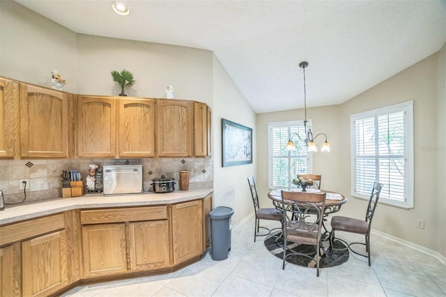17567 SE 81st Parnassus Ct, The Villages, FL 32162 - kitchen featuring lofted ceiling, tasteful backsplash, light countertops, a chandelier, and baseboards