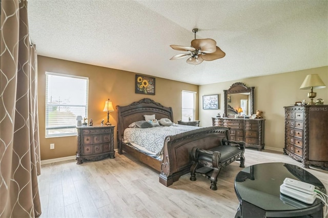 17567 SE 81st Parnassus Ct, The Villages, FL 32162 - bedroom with light wood-style flooring, a textured ceiling, a ceiling fan, and baseboards
