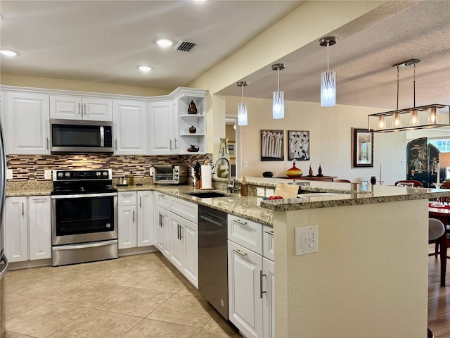 100 Bluff View Dr Unit 115C, Belleair Bluffs, FL 33770 - kitchen with stainless steel appliances, a peninsula, tasteful backsplash, white cabinets, and open shelves