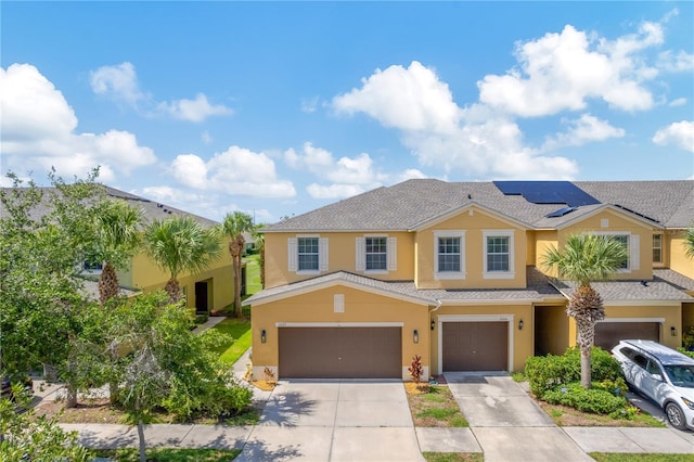 2022 Hawks View Dr, Ruskin, FL 33570 - townhome / multi-family property with stucco siding, an attached garage, concrete driveway, and roof mounted solar panels