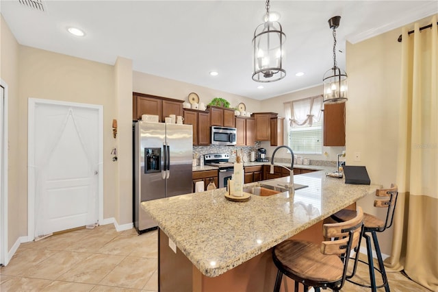 2022 Hawks View Dr, Ruskin, FL 33570 - kitchen with appliances with stainless steel finishes, a peninsula, a kitchen bar, hanging light fixtures, and light stone countertops