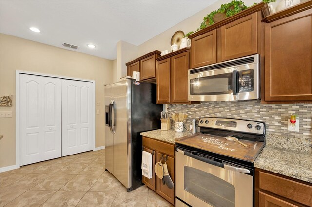 2022 Hawks View Dr, Ruskin, FL 33570 - kitchen with appliances with stainless steel finishes, brown cabinets, tasteful backsplash, and light tile patterned flooring