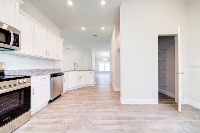 16425 66th Ln E, Parrish, FL 34219 - kitchen featuring appliances with stainless steel finishes, light stone counters, white cabinetry, recessed lighting, and a peninsula
