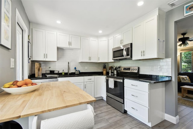 7219 4th Ave N, Saint Petersburg, FL 33710 - kitchen with stainless steel appliances, a sink, light wood-type flooring, white cabinetry, and recessed lighting