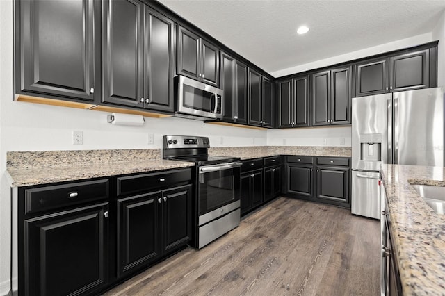 11434 Leland Groves Dr, Riverview, FL 33579 - kitchen featuring appliances with stainless steel finishes, dark cabinets, and a textured ceiling