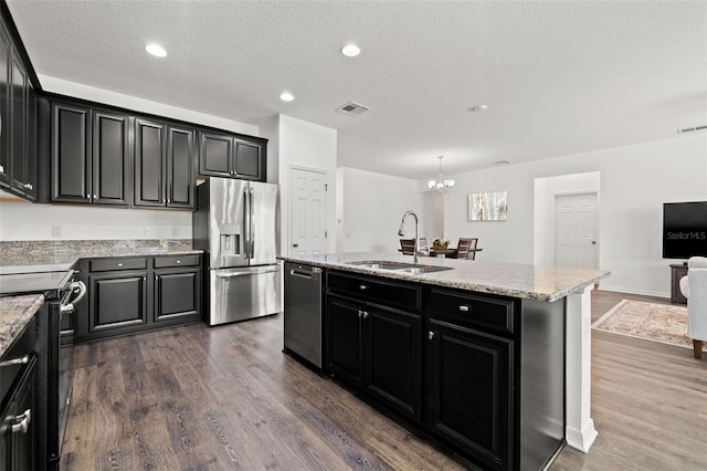 11434 Leland Groves Dr, Riverview, FL 33579 - kitchen featuring stainless steel appliances, dark cabinetry, dark wood-type flooring, an island with sink, and a chandelier