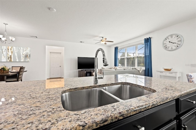 11434 Leland Groves Dr, Riverview, FL 33579 - kitchen featuring light stone counters, dark cabinetry, a chandelier, and ceiling fan