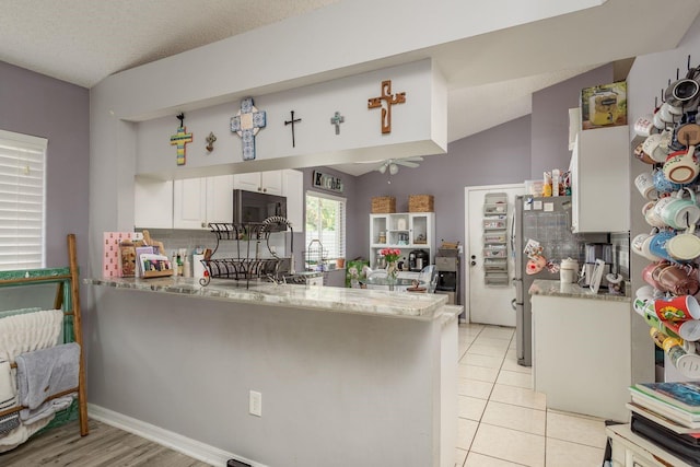 5826 Taywood Dr, Tampa, FL 33624 - kitchen with freestanding refrigerator, a peninsula, ceiling fan, white cabinetry, and light stone counters
