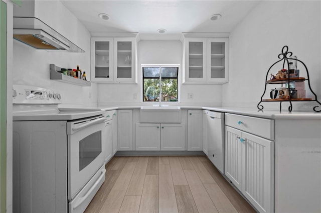 7705 4th Ave W, Bradenton, FL 34209 - kitchen featuring white electric range, dishwashing machine, wall chimney range hood, light wood finished floors, and white cabinetry