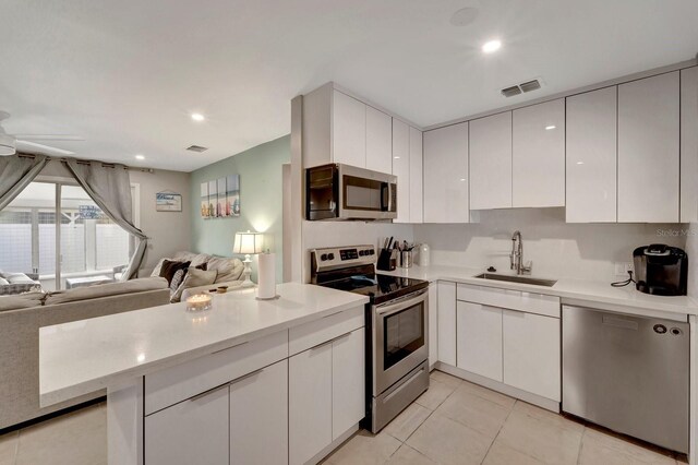551 Lindley Ter, Port Charlotte, FL 33952 - kitchen with stainless steel appliances, a sink, open floor plan, white cabinetry, and light tile patterned floors
