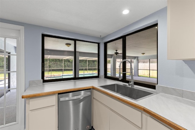 14164 Fennsbury Dr, Tampa, FL 33624 - kitchen featuring stainless steel dishwasher, a sink, light countertops, and white cabinetry