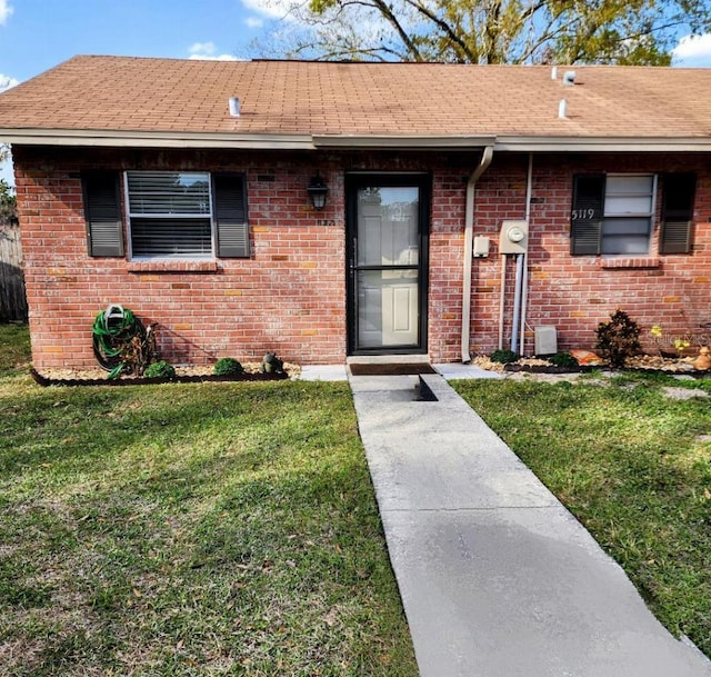 5119 Hector Ct, Tampa, FL 33624 - view of front of house featuring a front lawn, brick siding, and roof with shingles