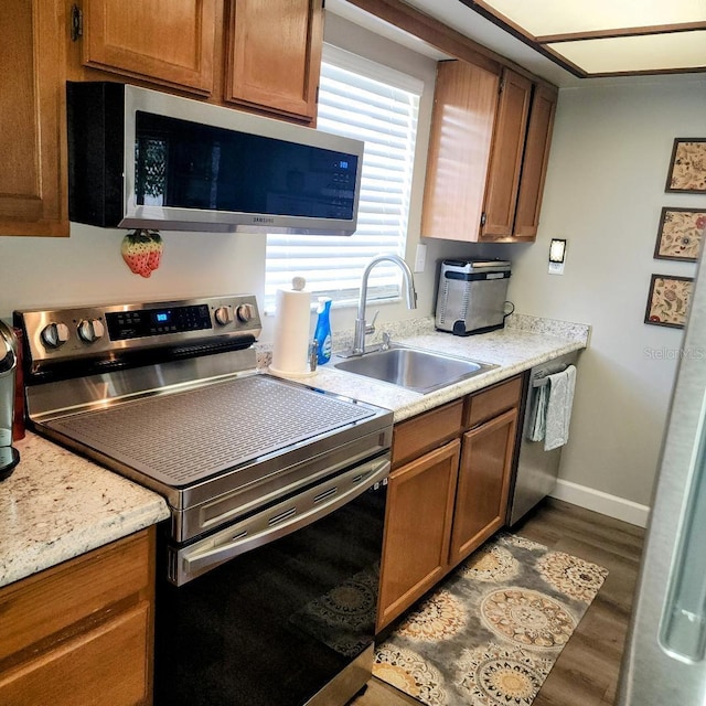 5119 Hector Ct, Tampa, FL 33624 - kitchen featuring stainless steel appliances, a sink, dark wood-style floors, baseboards, and brown cabinetry