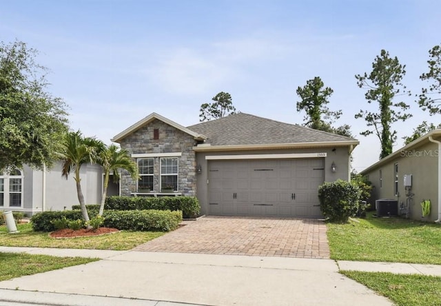 1553 Amber Leaf Cir, Ocoee, FL 34761 - view of front of home with central AC, decorative driveway, a garage, stone siding, and a front lawn
