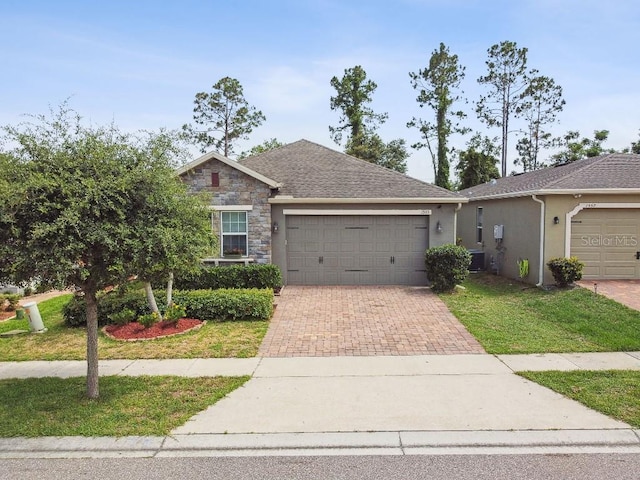 1553 Amber Leaf Cir, Ocoee, FL 34761 - view of front of property featuring a garage, decorative driveway, a front lawn, central air condition unit, and stucco siding