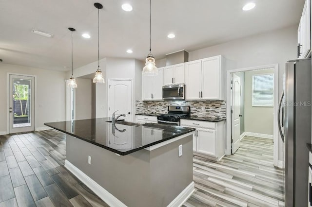 1553 Amber Leaf Cir, Ocoee, FL 34761 - kitchen with stainless steel appliances, light wood-style floors, baseboards, tasteful backsplash, and white cabinets