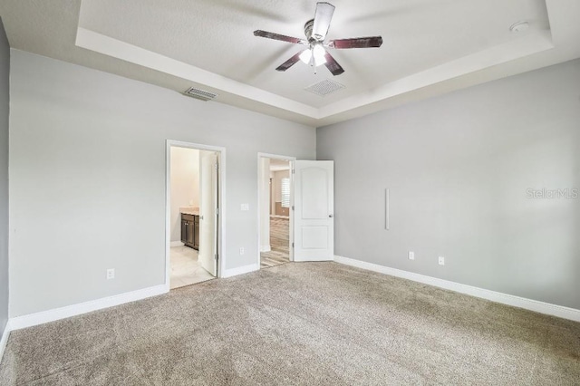 1553 Amber Leaf Cir, Ocoee, FL 34761 - unfurnished bedroom featuring a tray ceiling, light carpet, ensuite bathroom, baseboards, and ceiling fan