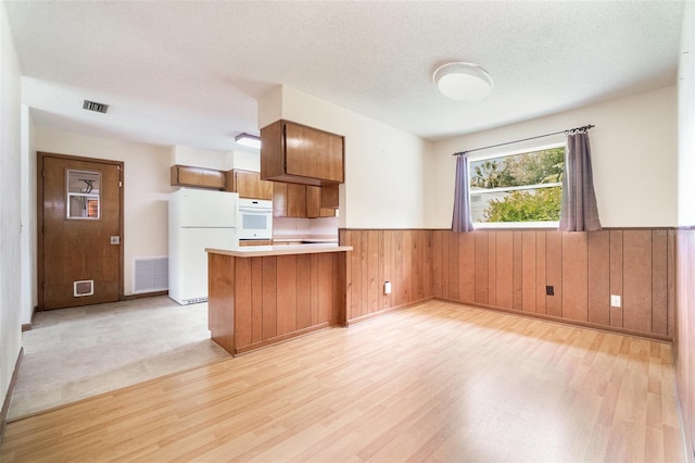 201 W New York Ave, Orange City, FL 32763 - kitchen with white appliances, wainscoting, brown cabinets, light wood finished floors, and a peninsula