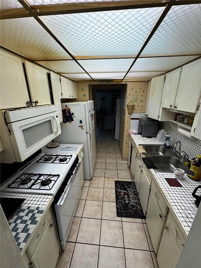 5247 81st St N Unit 2, Saint Petersburg, FL 33709 - kitchen featuring white appliances, tile countertops, light tile patterned floors, and a sink