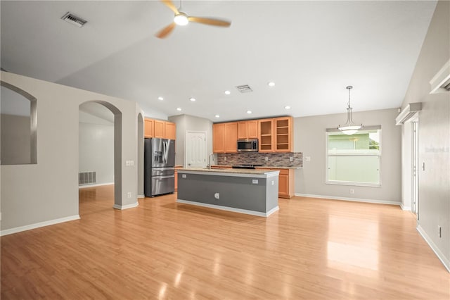 826 Addison Dr NE, Saint Petersburg, FL 33716 - kitchen featuring appliances with stainless steel finishes, ceiling fan, light wood-style flooring, tasteful backsplash, and arched walkways