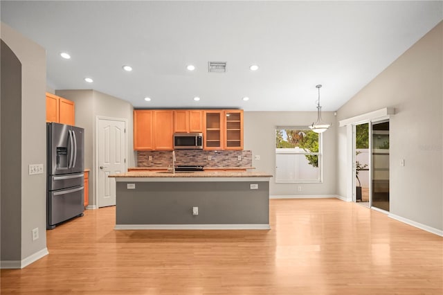 826 Addison Dr NE, Saint Petersburg, FL 33716 - kitchen with stainless steel appliances, light wood finished floors, tasteful backsplash, glass insert cabinets, and a kitchen island with sink