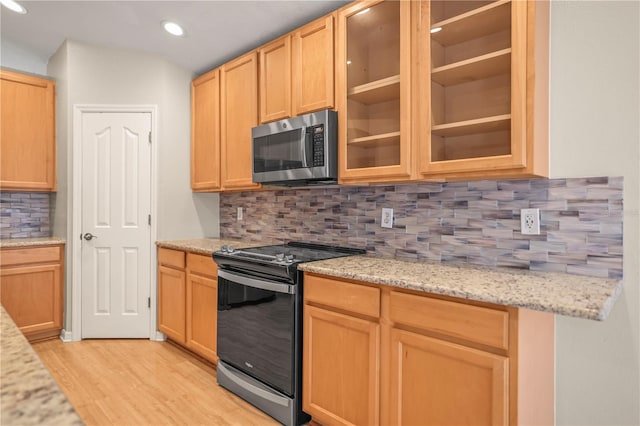 826 Addison Dr NE, Saint Petersburg, FL 33716 - kitchen with appliances with stainless steel finishes, decorative backsplash, light wood-style flooring, light brown cabinetry, and glass insert cabinets