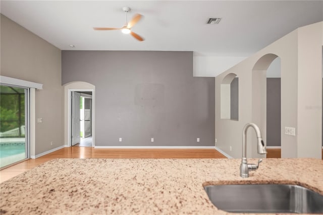 826 Addison Dr NE, Saint Petersburg, FL 33716 - kitchen featuring light wood-style flooring, ceiling fan, and light stone counters