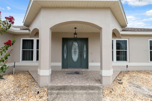 13238 Asbury St, Spring Hill, FL 34609 - view of exterior entry featuring stucco siding and a shingled roof
