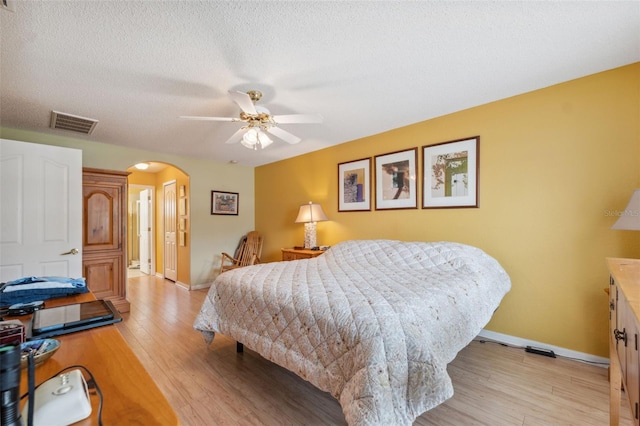 13238 Asbury St, Spring Hill, FL 34609 - bedroom with arched walkways, baseboards, light wood-type flooring, a closet, and a textured ceiling