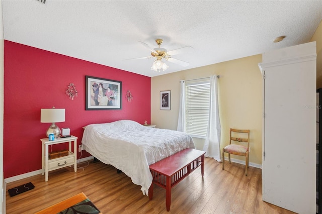 13238 Asbury St, Spring Hill, FL 34609 - bedroom featuring an accent wall, light wood-style floors, a textured ceiling, baseboards, and a ceiling fan