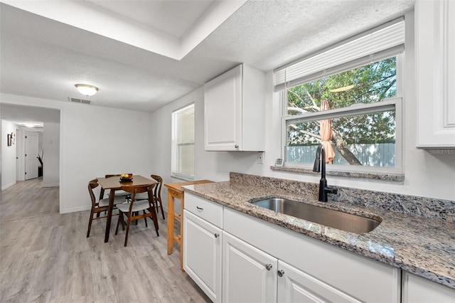 4922 Bola St, New Port Richey, FL 34652 - kitchen with light wood-style floors, white cabinetry, a textured ceiling, and light stone counters