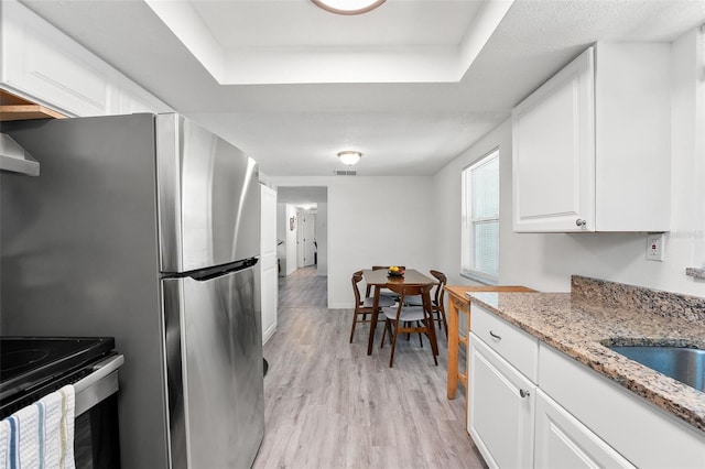 4922 Bola St, New Port Richey, FL 34652 - kitchen with a tray ceiling, light wood-style floors, white cabinetry, light stone counters, and stainless steel appliances