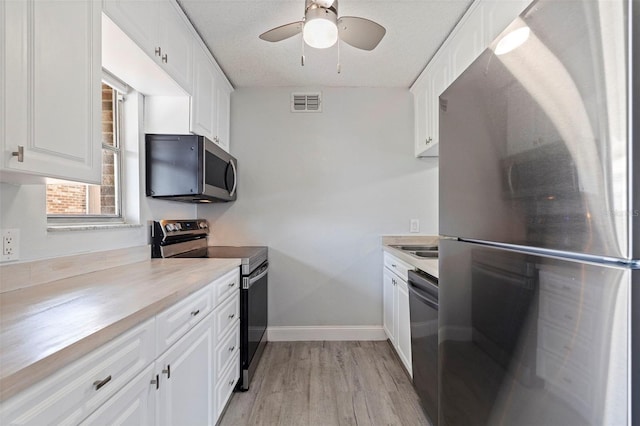 10423 Carrollbrook Cir Unit 203, Tampa, FL 33618 - kitchen with appliances with stainless steel finishes, a ceiling fan, light wood-style floors, white cabinets, and light countertops