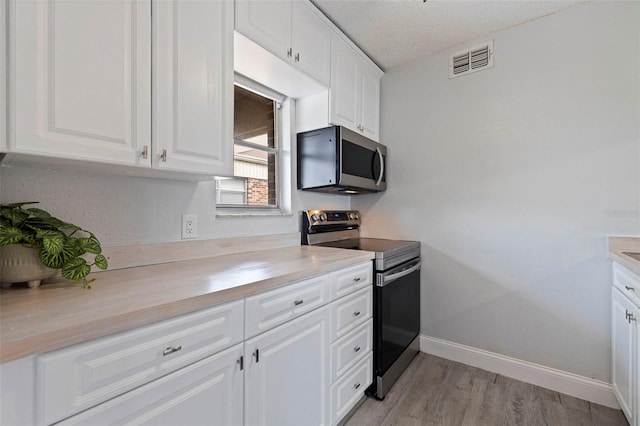 10423 Carrollbrook Cir Unit 203, Tampa, FL 33618 - kitchen featuring stainless steel appliances, light countertops, white cabinets, light wood-style floors, and baseboards