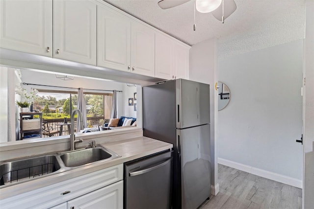 10423 Carrollbrook Cir Unit 203, Tampa, FL 33618 - kitchen featuring stainless steel appliances, a sink, light wood-style floors, white cabinets, and baseboards