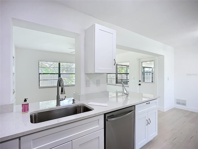 21426 Quesada Ave, Port Charlotte, FL 33952 - kitchen with dishwasher, light stone counters, white cabinets, light wood finished floors, and a peninsula