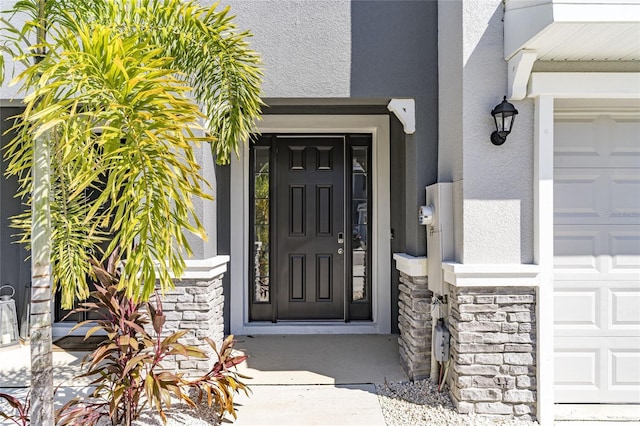 2801 Midnight Pearl Dr, Sarasota, FL 34240 - view of exterior entry featuring stucco siding, stone siding, and a garage