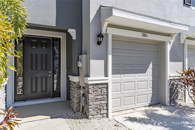 2801 Midnight Pearl Dr, Sarasota, FL 34240 - view of exterior entry with stucco siding, a garage, and driveway