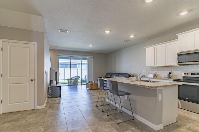 2801 Midnight Pearl Dr, Sarasota, FL 34240 - kitchen featuring appliances with stainless steel finishes, open floor plan, an island with sink, light stone counters, and a sink