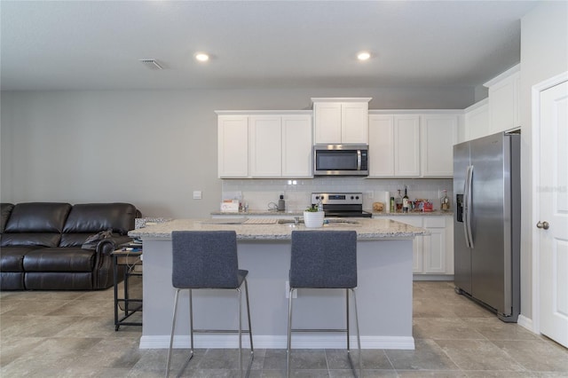 2801 Midnight Pearl Dr, Sarasota, FL 34240 - kitchen with stainless steel appliances, open floor plan, white cabinets, a kitchen breakfast bar, and backsplash