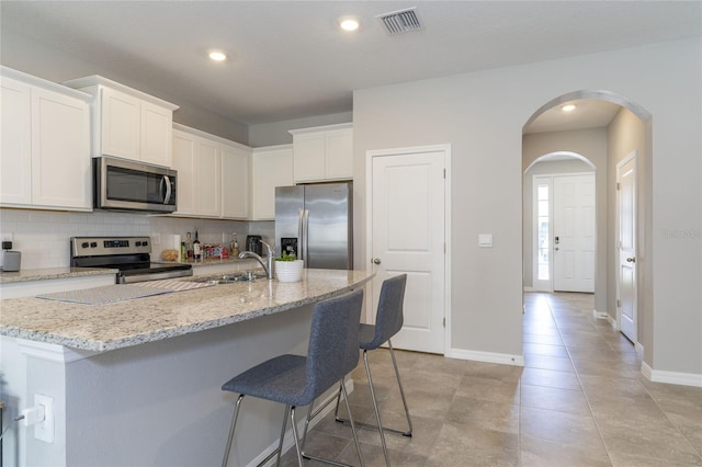 2801 Midnight Pearl Dr, Sarasota, FL 34240 - kitchen featuring stainless steel appliances, backsplash, a breakfast bar area, white cabinets, and baseboards