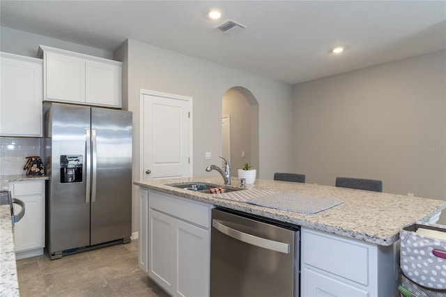 2801 Midnight Pearl Dr, Sarasota, FL 34240 - kitchen featuring stainless steel appliances, a sink, arched walkways, white cabinets, and an island with sink