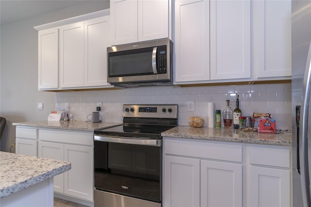 2801 Midnight Pearl Dr, Sarasota, FL 34240 - kitchen featuring appliances with stainless steel finishes, tasteful backsplash, white cabinetry, and light stone counters