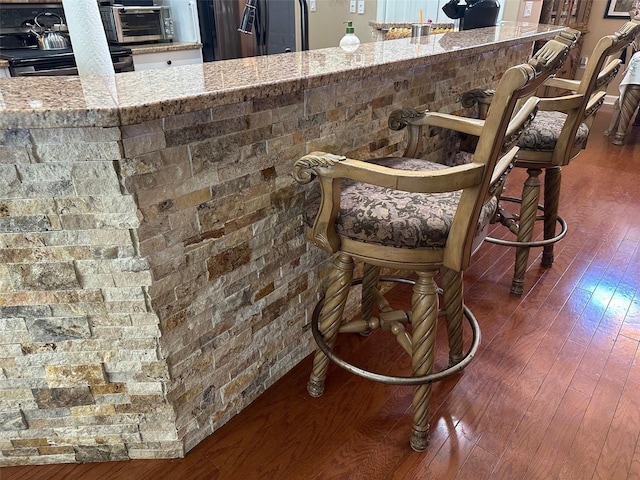 13807 Eagles Rock Ct, Hudson, FL 34667 - detailed view of wood finished floors, electric stove, and black fridge with ice dispenser
