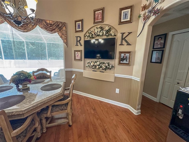 13807 Eagles Rock Ct, Hudson, FL 34667 - dining area featuring a chandelier, wood finished floors, arched walkways, wainscoting, and baseboards