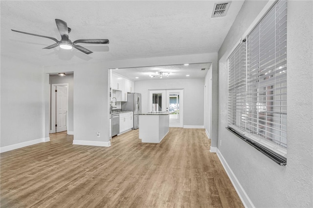 223 Pinehurst Dr, Auburndale, FL 33823 - unfurnished living room featuring light wood-type flooring, a ceiling fan, and a textured ceiling